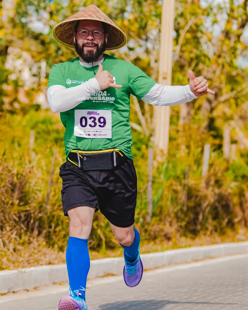 Pyerry Diniz correndo na Corrida de Aniversário de Belo Jardim, de chapéu de palha